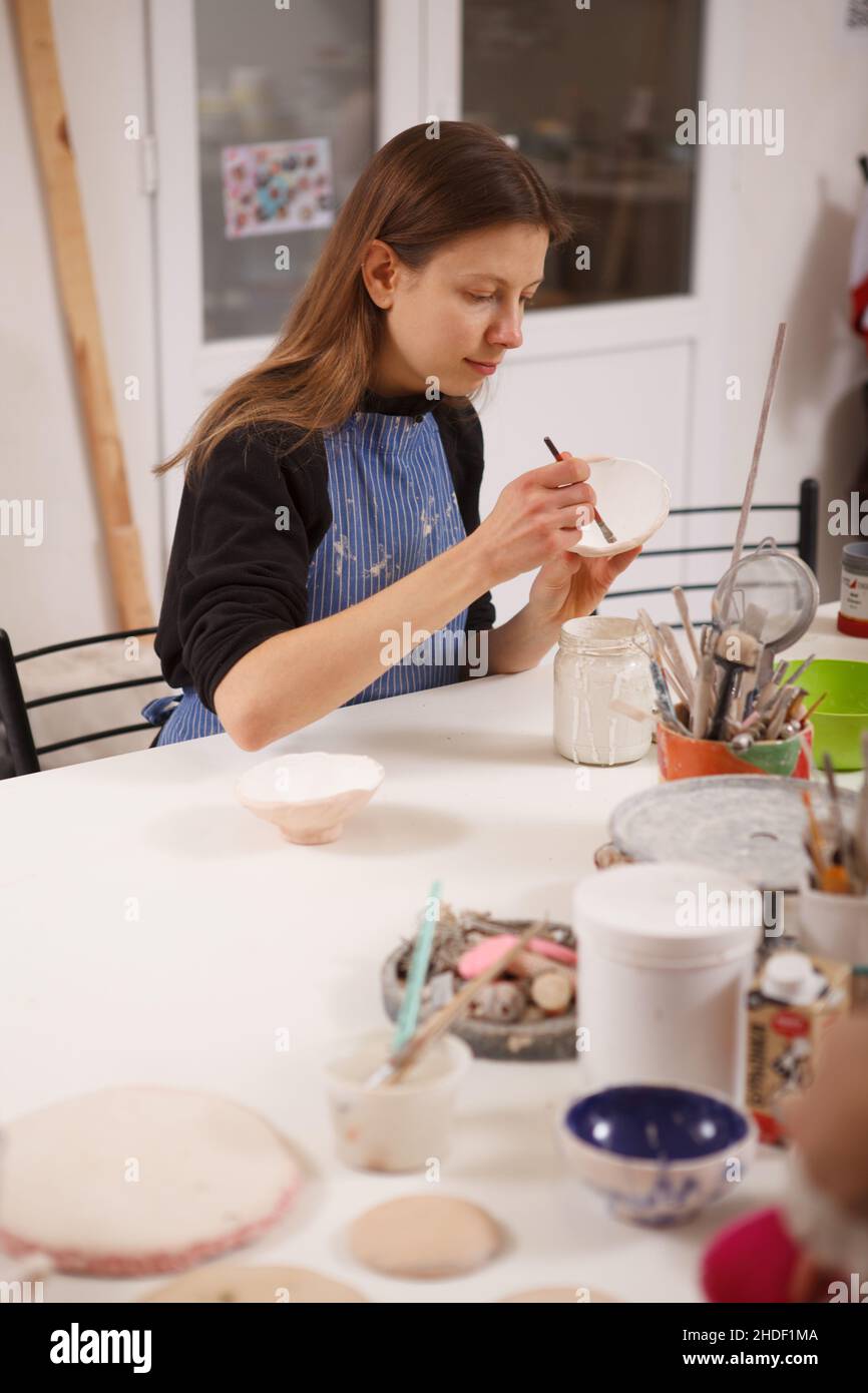 Scatto verticale di un artista femminile che decora la ciotola di ceramica allo studio di ceramica Foto Stock
