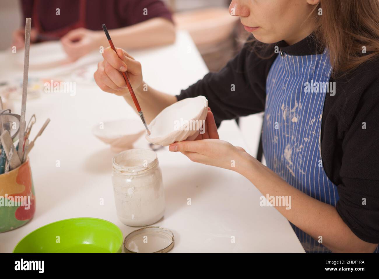 Scatto corto di una donna che dipinge ciotola di ceramica, lavorando allo studio di ceramica Foto Stock