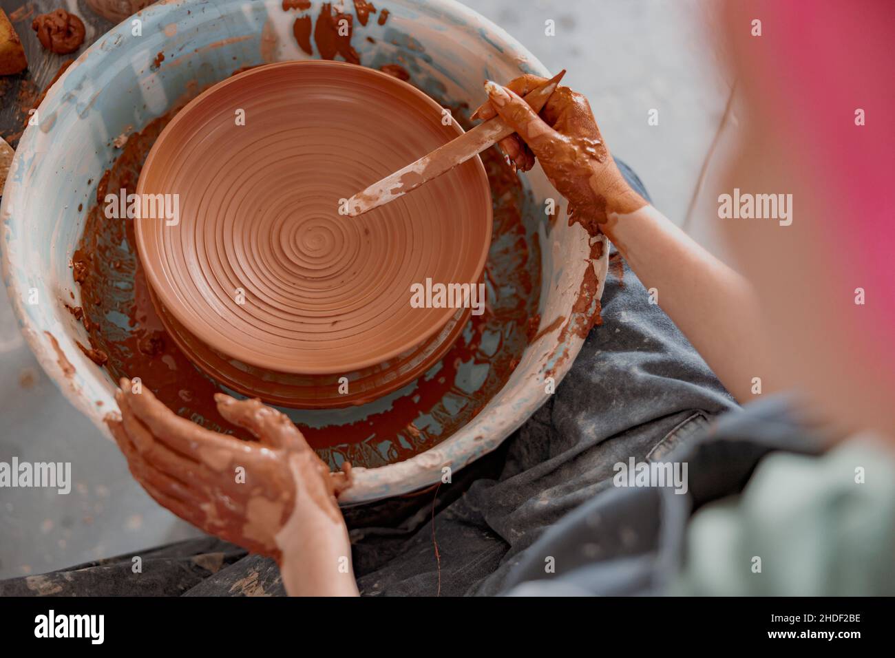 Potter che lavora manualmente su una ruota di ceramica in sala di lavoro Foto Stock