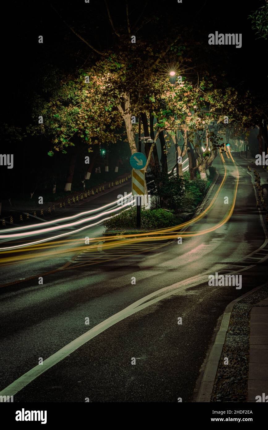 Esposizione verticale lunga delle luci dell'automobile su una strada rurale scura Foto Stock