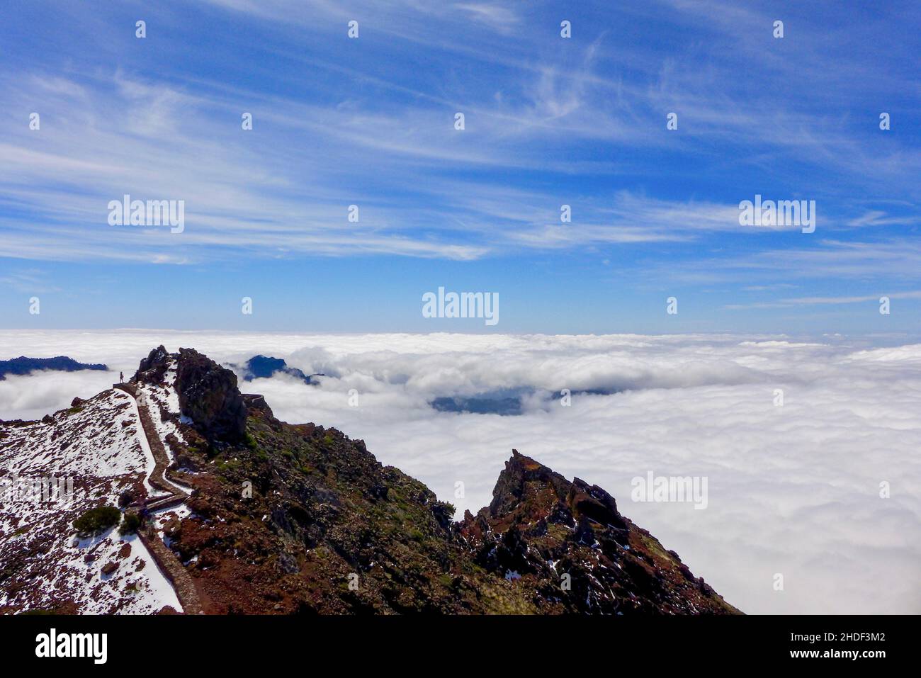 Lone escursionista cammina il sentiero a Roque de los Muchachos in una giornata luminosa e soleggiata. La vista sulla caldera vulcanica è coperta da un'inversione di nuvola. La Palma Foto Stock