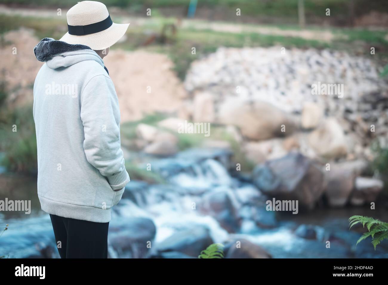 donna anziana che si rilassa vicino al torrente nel parco Foto Stock