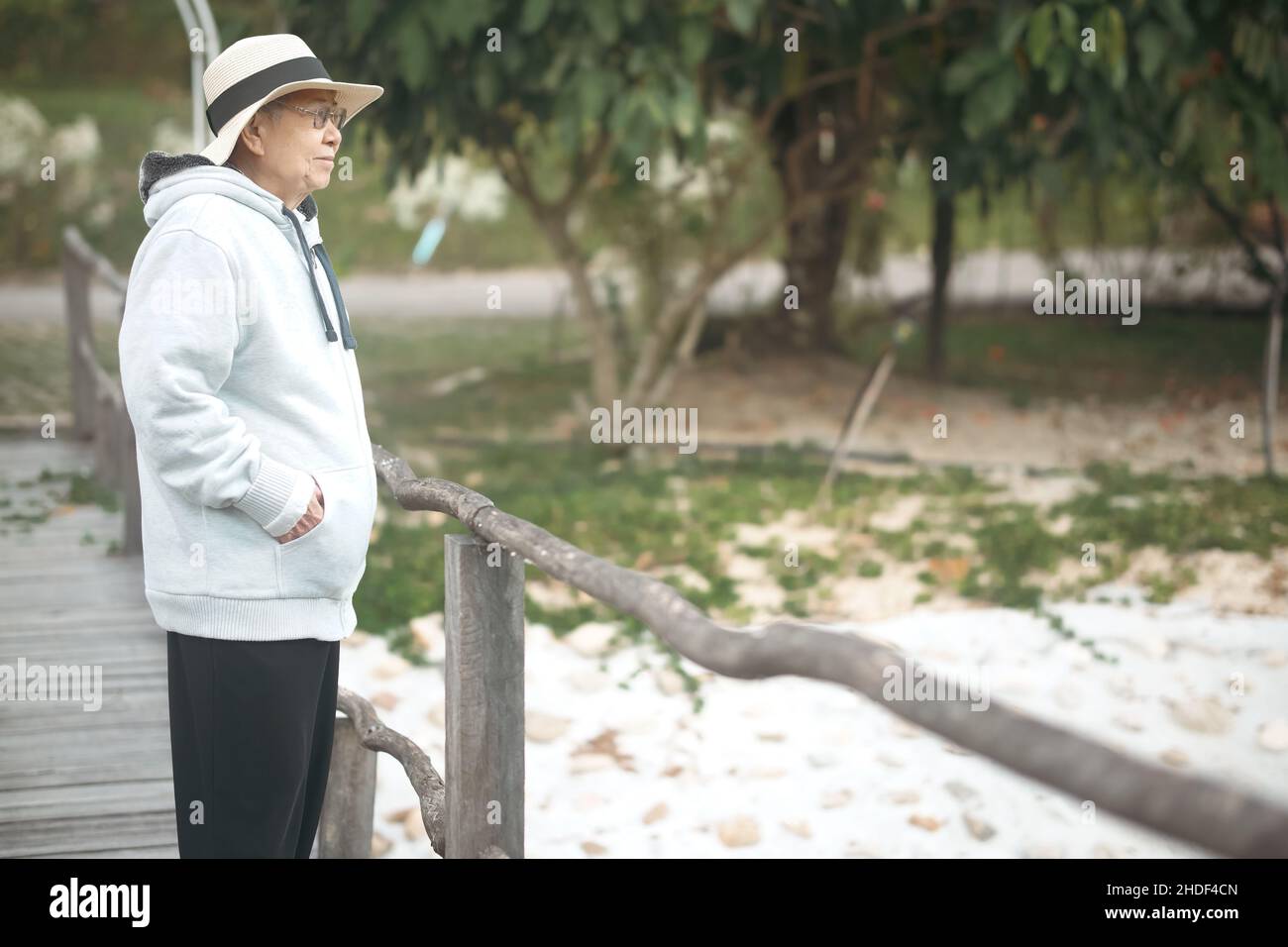 donna anziana che cammina rilassandosi sul ponte nel parco Foto Stock