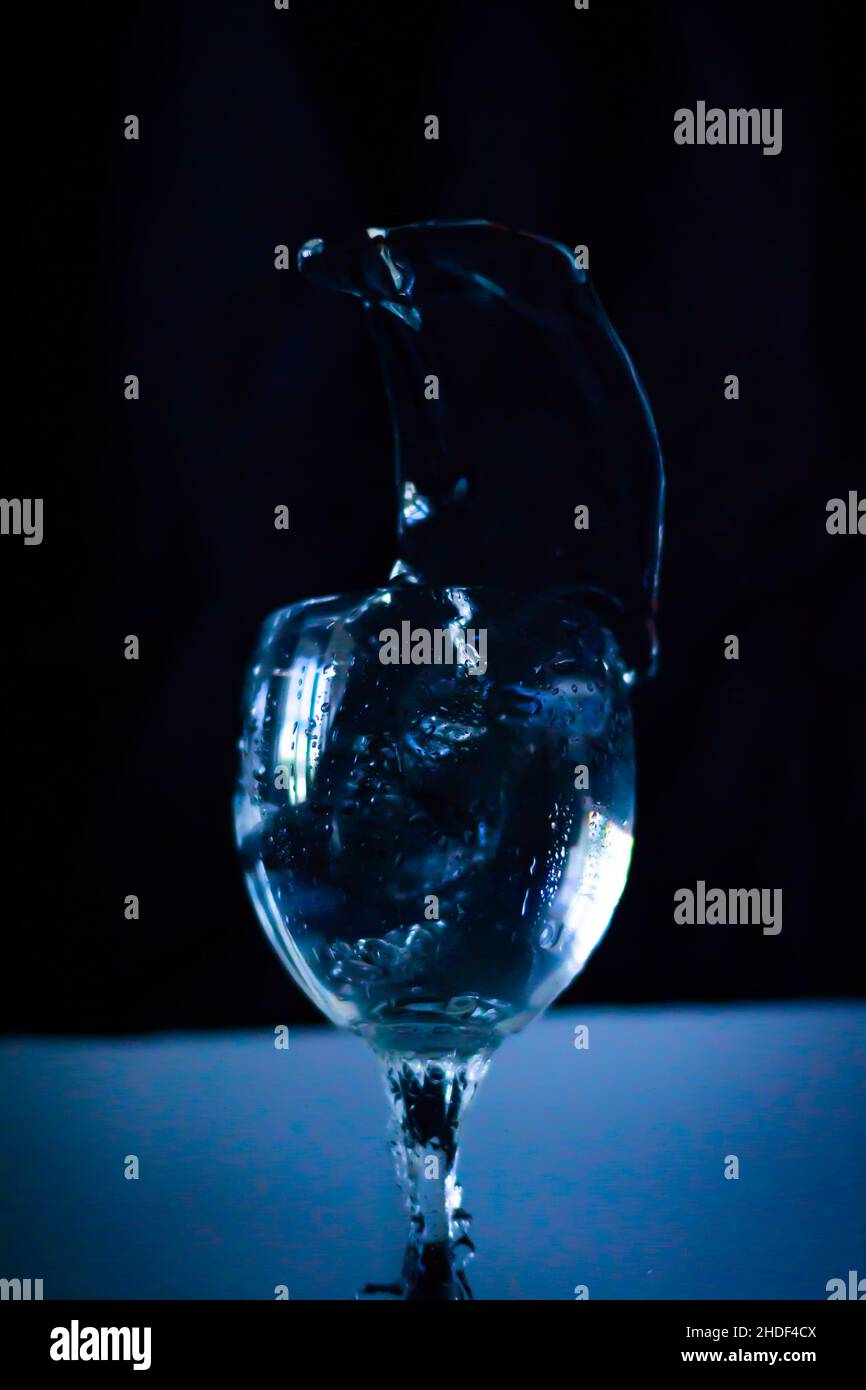 Scatto verticale di un bicchiere mezzo pieno isolato su sfondo nero Foto Stock