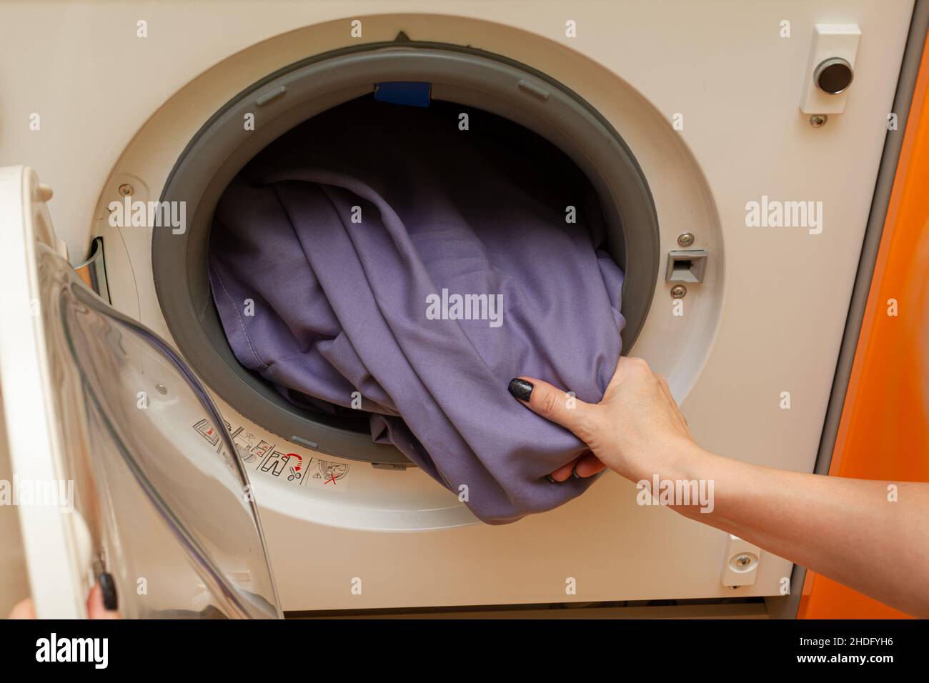 la mano della donna estrae la lavanderia dalla lavatrice Foto Stock