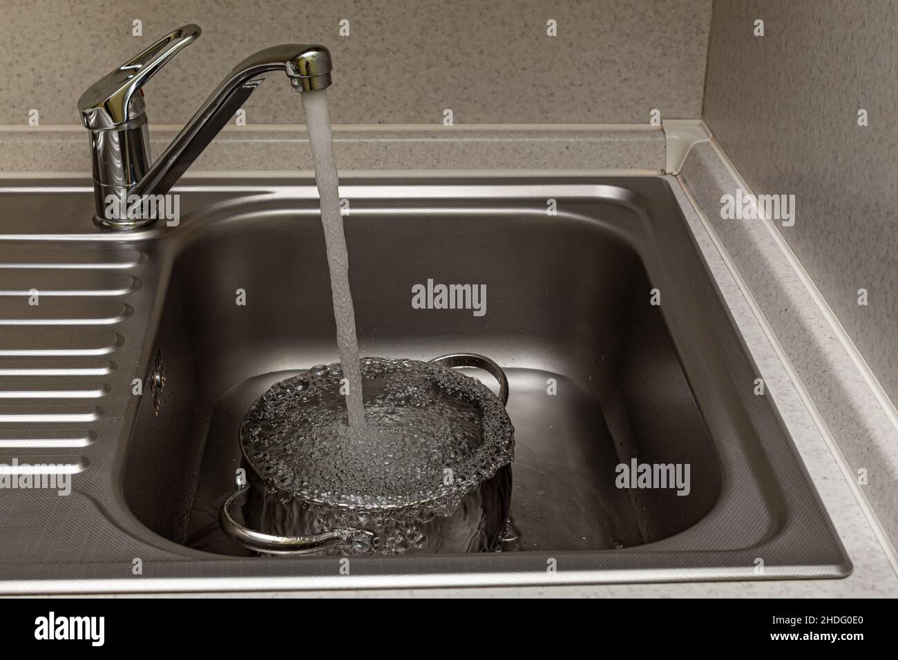 l'acqua del rubinetto è versata nella padella nel lavandino Foto Stock