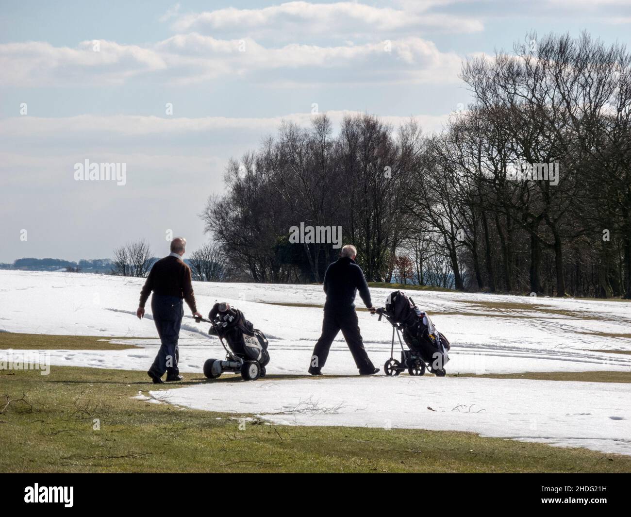 I golfisti invernali sfidano gli elementi sui fairway parzialmente innevati Foto Stock