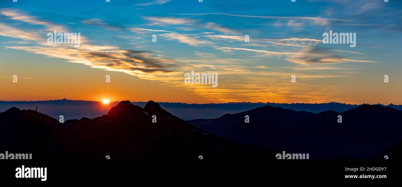 Splendido tramonto drammatico visto dalle montagne in Italia con le nuvole illuminate da ultimi raggi arancioni, panorama Foto Stock