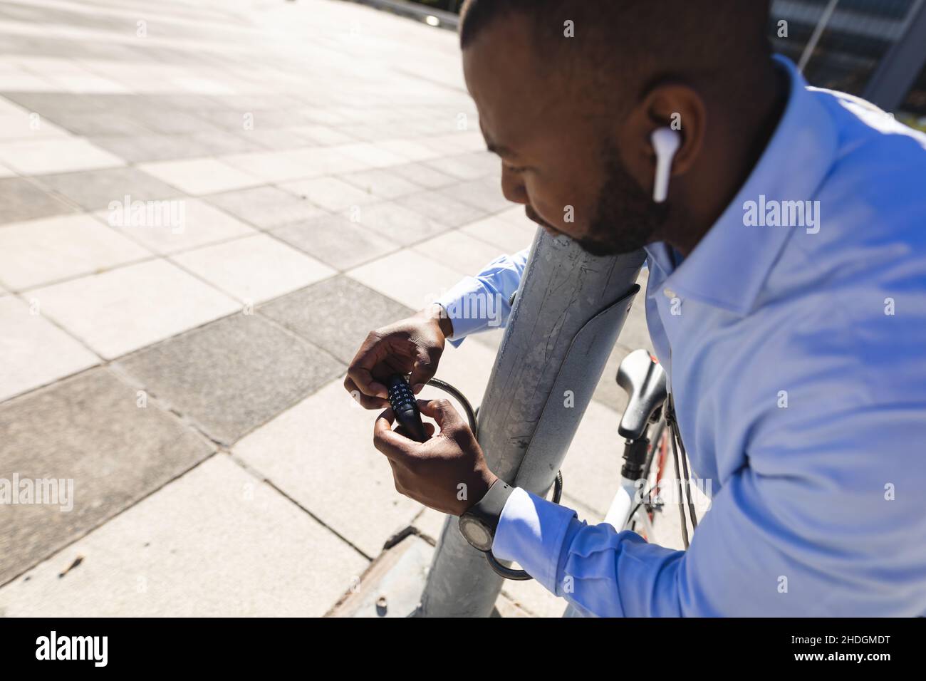 Un uomo d'affari afro-americano che blocca la sua bicicletta al parco aziendale quando si va in ufficio Foto Stock