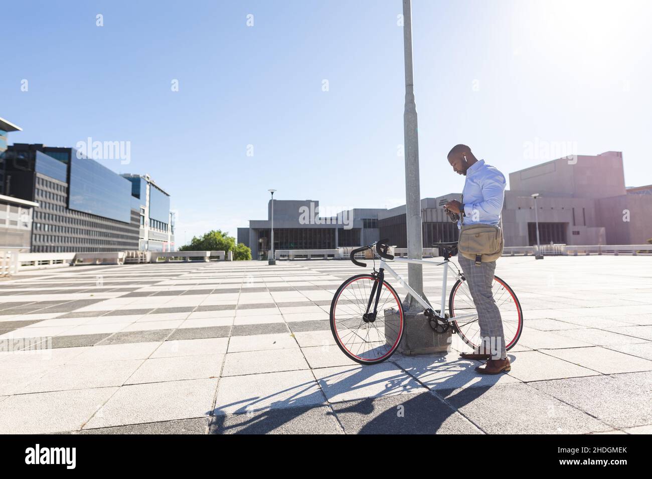 Un uomo d'affari afro-americano che blocca la sua bicicletta al parco aziendale quando si va in ufficio Foto Stock