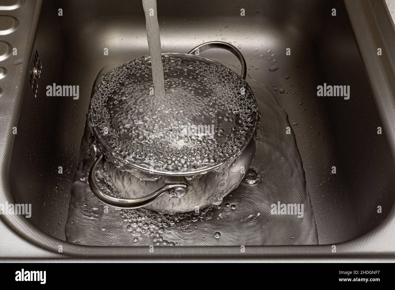 l'acqua del rubinetto è versata nella padella nel lavandino Foto Stock