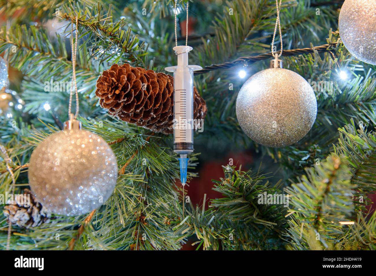 Coronavirus pandemic - Una siringa di vaccino di Covid-19 Booster appesa su un albero di Natale Foto Stock