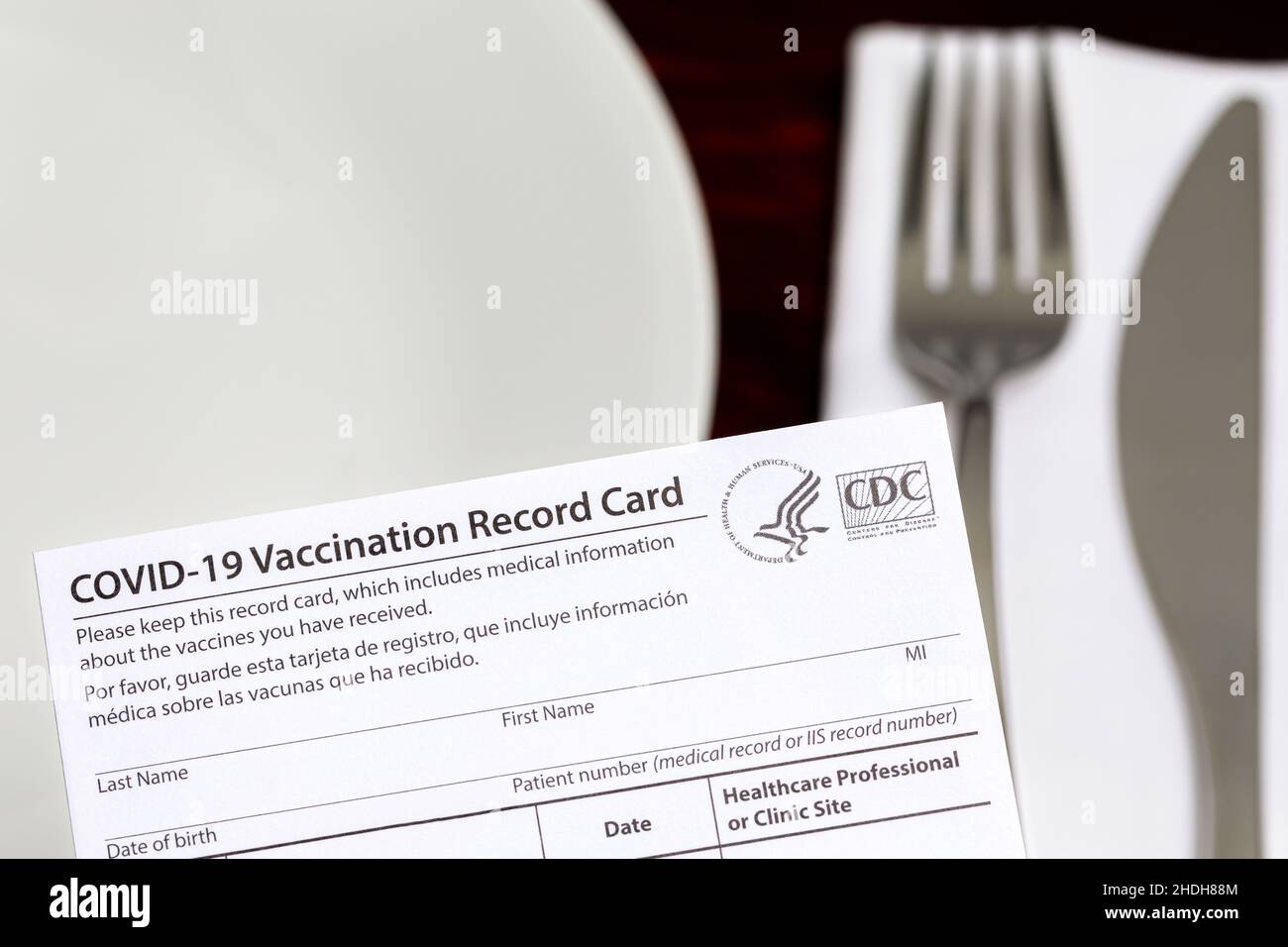 Scheda di vaccinazione Covid-19 e tavolo da ristorante. Mandato vaccinale indoor, restrizioni di intrattenimento e concetto di requisito di vaccinazione. Foto Stock