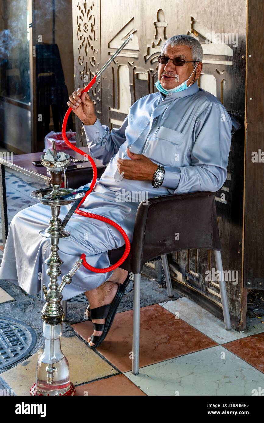 Adulto anziano Fumare Un Shisha Pipe in the Street, Aqaba, Aqaba Governorate, Giordania. Foto Stock