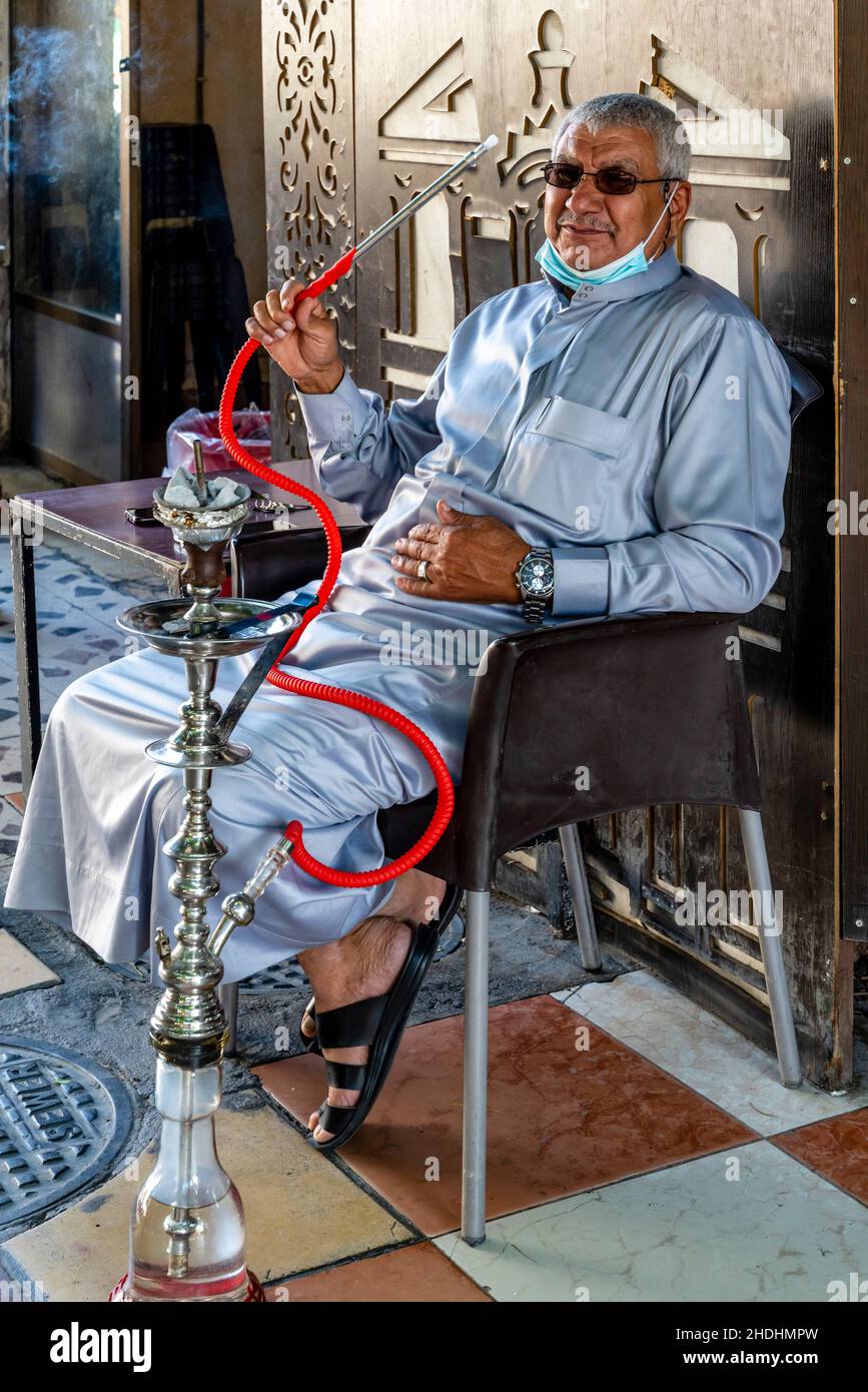 Adulto anziano Fumare Un Shisha Pipe in the Street, Aqaba, Aqaba Governorate, Giordania. Foto Stock