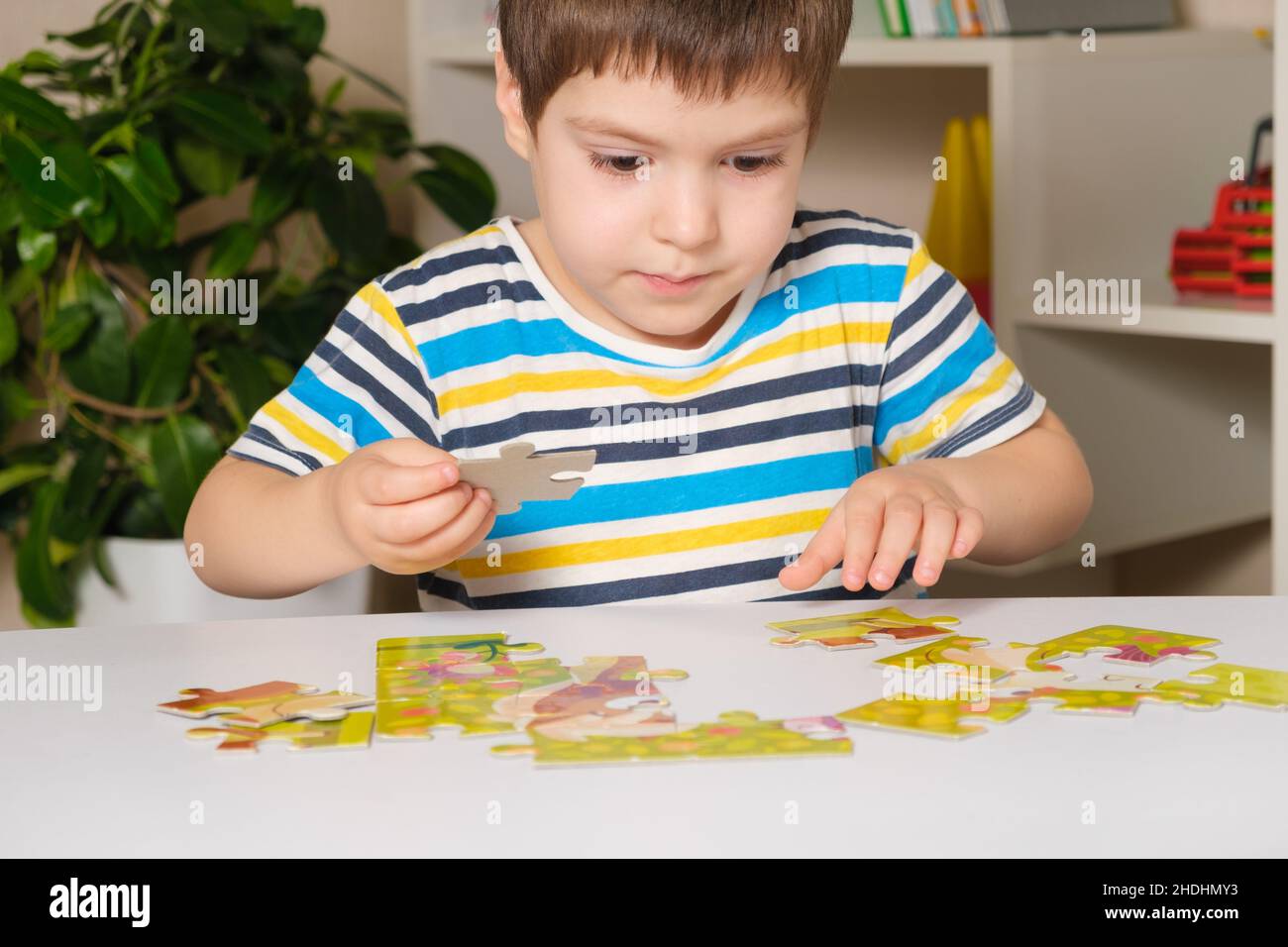 Un preschooler suona puzzle, mette insieme un'immagine Foto Stock