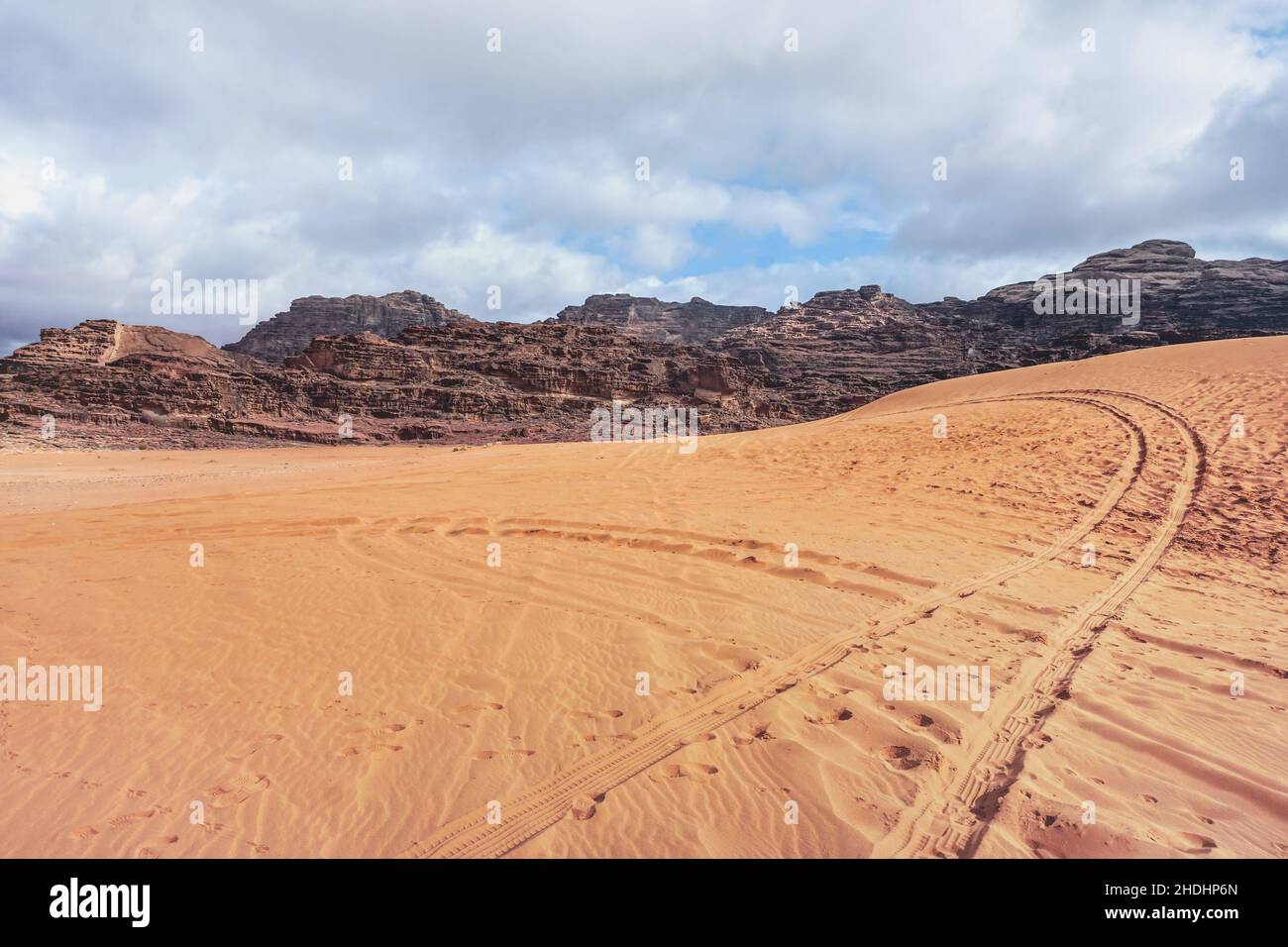 Massicci rocciosi sul deserto rosso, tracce di veicoli stampati in sabbia, scenario tipico a Wadi Rum, Giordania Foto Stock