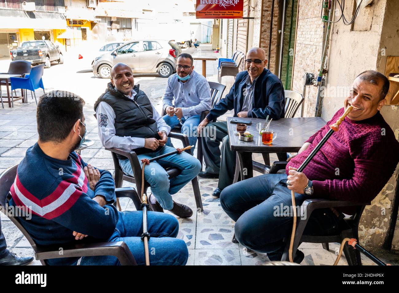 Un gruppo di uomini si siede intorno Ad Un tavolo che chiacchiera e fuma Shisha Pipes, Aqaba, governorato di Aqaba, Giordania. Foto Stock