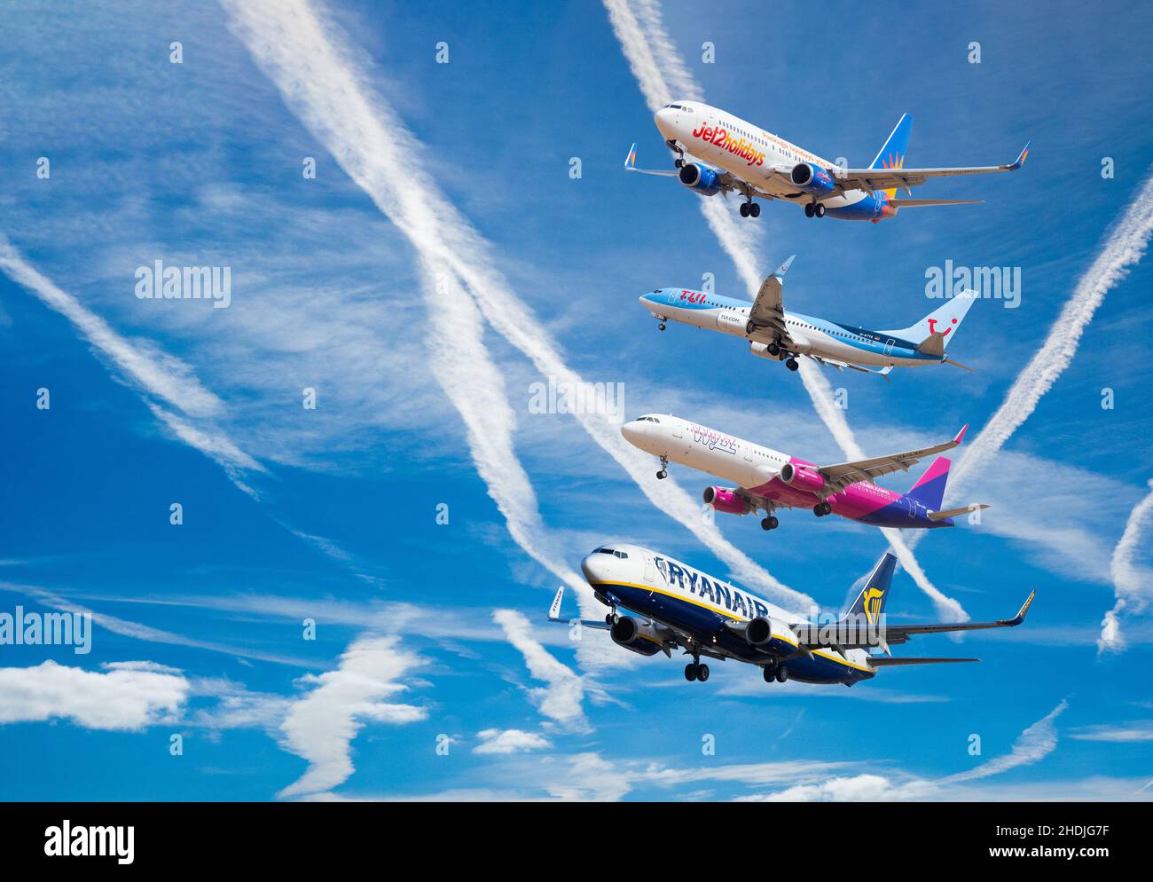 Jet 2, Tui, Ryanair e Wizzair, aerei contro il cielo blu. Industria aeronautica, riscaldamento globale, cambiamento climatico, prezzi delle azioni in aumento. Concetto Foto Stock
