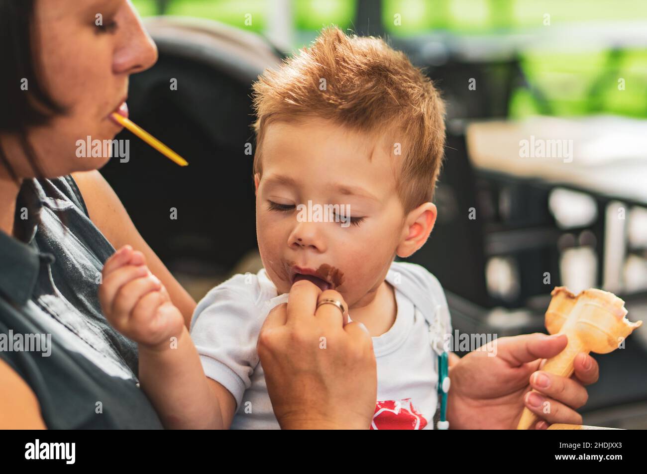 Ragazzo giovane che mangia gelato al cioccolato con la madre Foto Stock