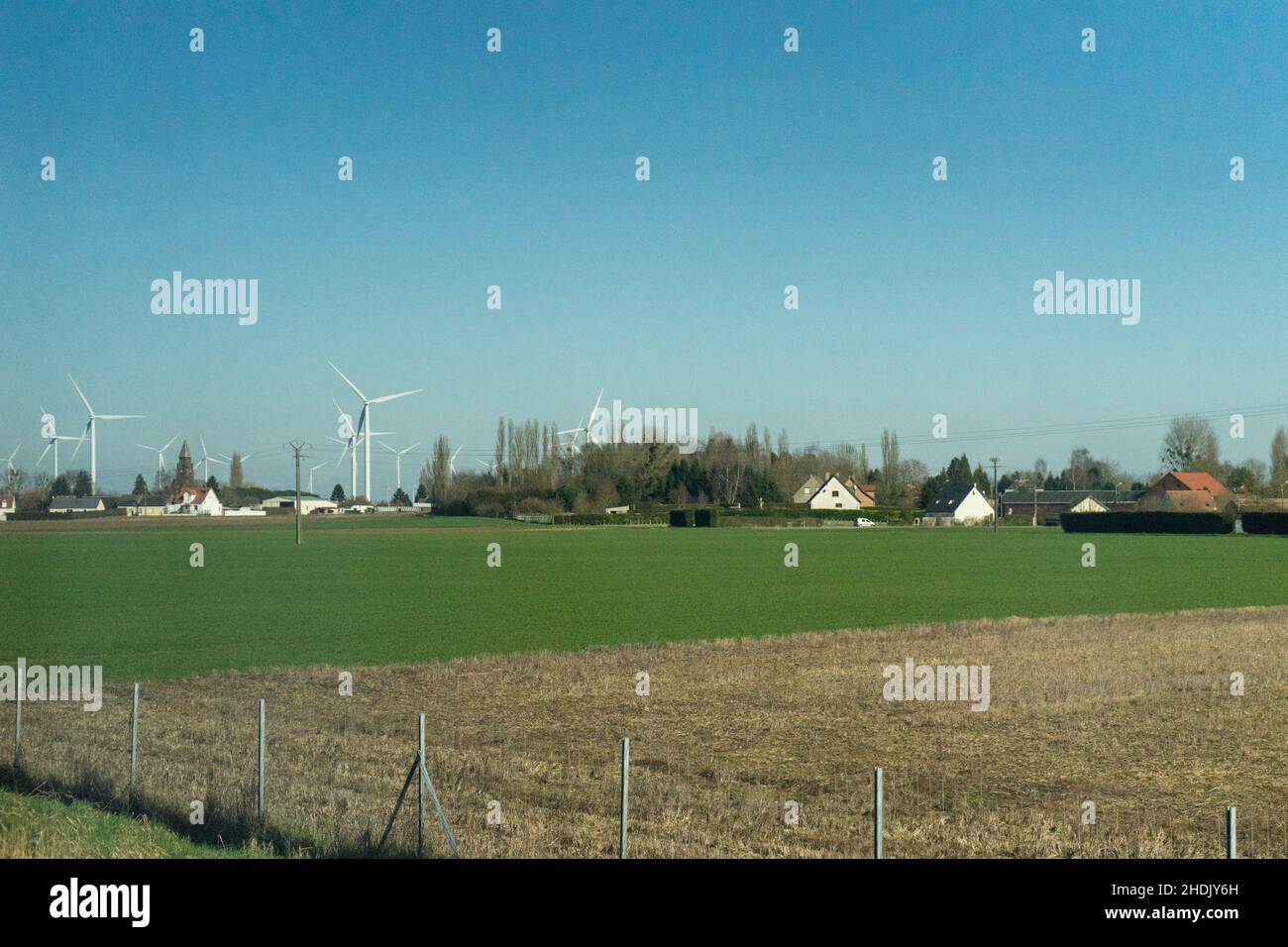 Campo con turbine eoliche ed edifici di fattoria contro il cielo nuvoloso e luminoso con spazio copia Foto Stock