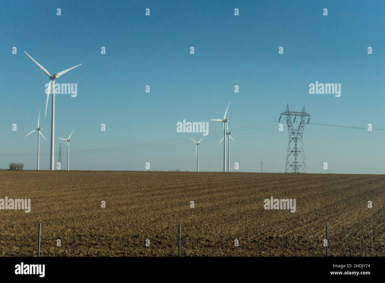 Campo con turbine eoliche contro il cielo nuvoloso e luminoso con spazio copia Foto Stock