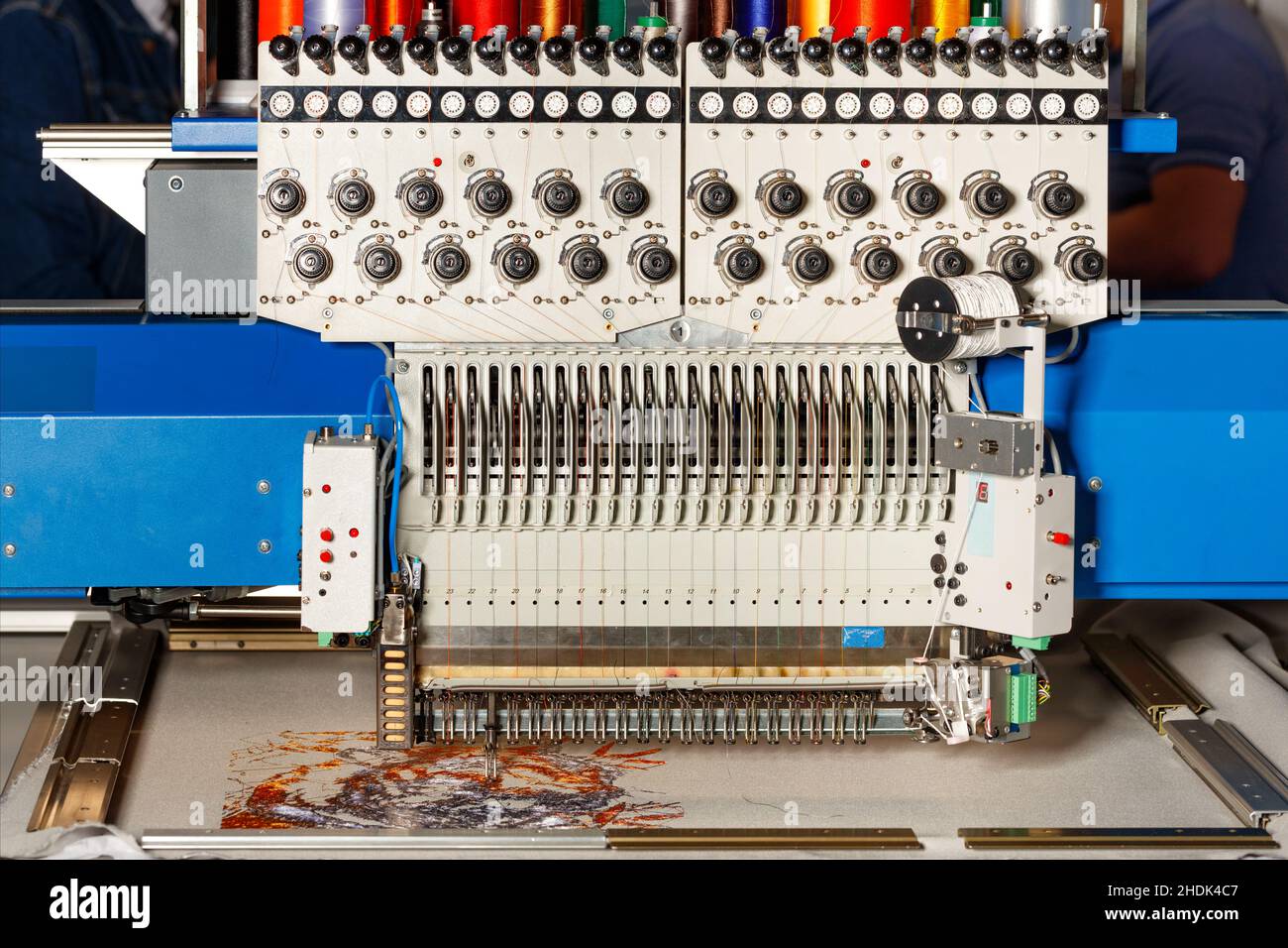 Macchina da ricamo programmabile industriale con fili multicolore al lavoro. Primo piano. Spazio di copia. Foto Stock