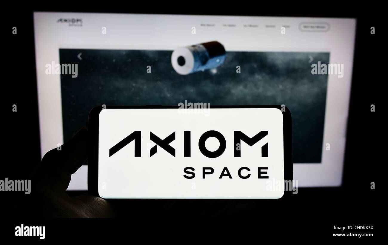 Persona che tiene il cellulare con il logo della società aerospaziale americana Axiom Space Inc. Sullo schermo di fronte al sito web aziendale. Mettere a fuoco sul display del telefono. Foto Stock