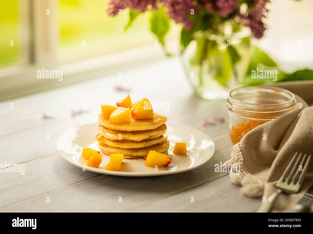 Pancake con pesca tagliata a colazione, persona in background Foto Stock Pancake con pesca tagliata a colazione, persona in background Foto Stock