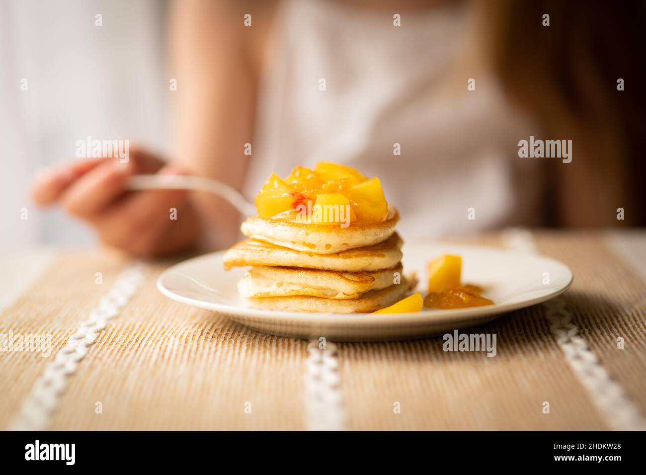 Pancake con pesca tagliata a colazione, persona in background Foto Stock Pancake con pesca tagliata a colazione, persona in background Foto Stock