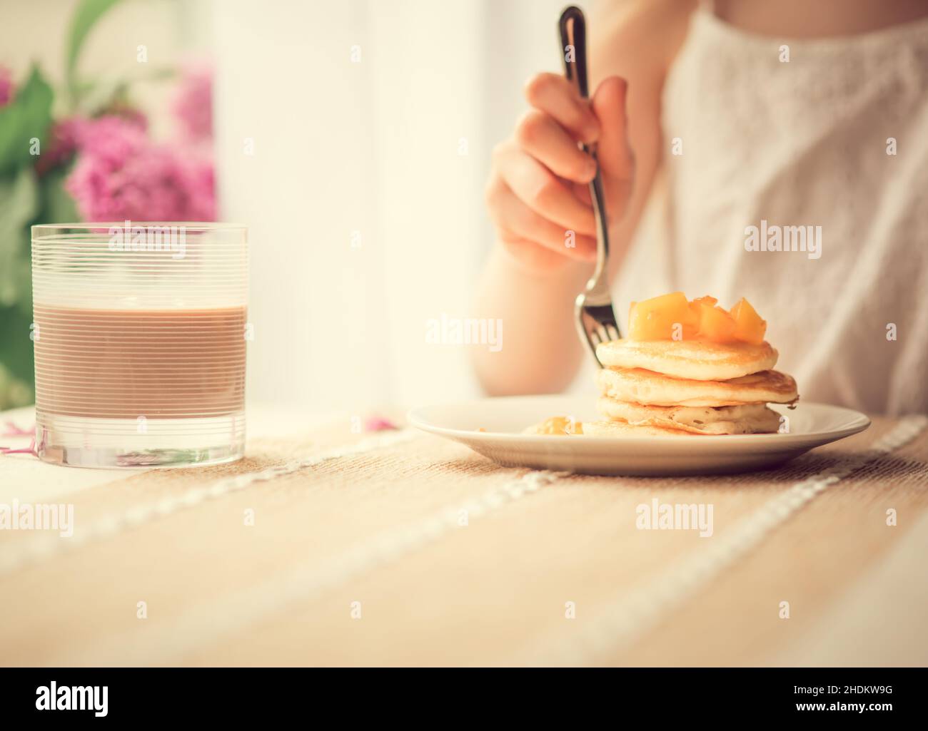 Pancake con pesca tagliata a colazione, persona in background Foto Stock Pancake con pesca tagliata a colazione, persona in background Foto Stock