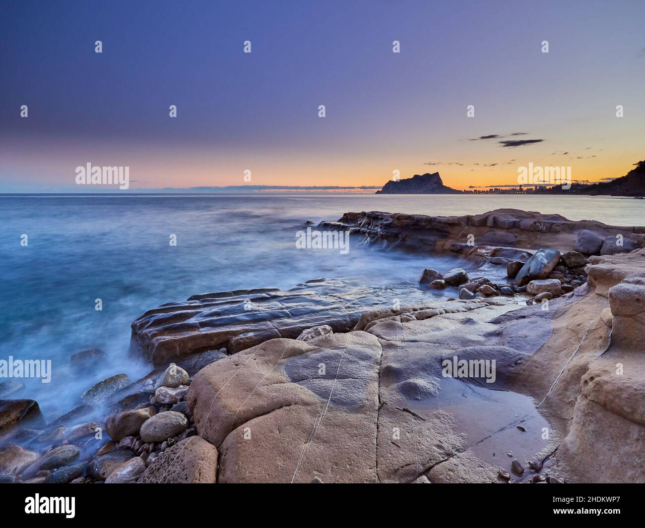 Vista panoramica delle rocce che escono dall'acqua sotto un cielo color tramonto in una lunga esposizione - carta da parati Foto Stock