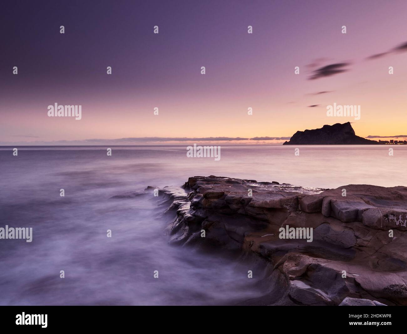Vista panoramica delle rocce che escono dalla nebbia sotto un cielo color tramonto in una lunga esposizione - carta da parati Foto Stock