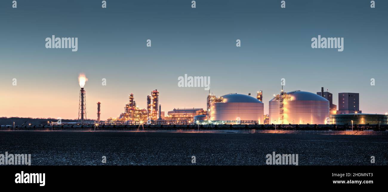 Grande impianto di produzione di fertilizzanti in un paesaggio rurale al crepuscolo. Le autocisterne ferroviarie sono allineate in primo piano. Foto Stock