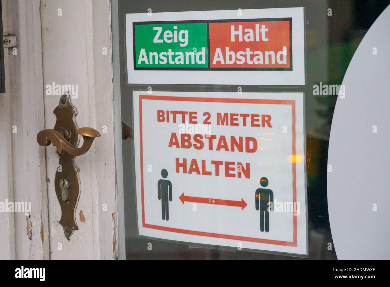 Primo piano adesivo di avvertimento di 2 metri sociale distanziamento e spingere / tirare sulla porta in lingua tedesca Foto Stock