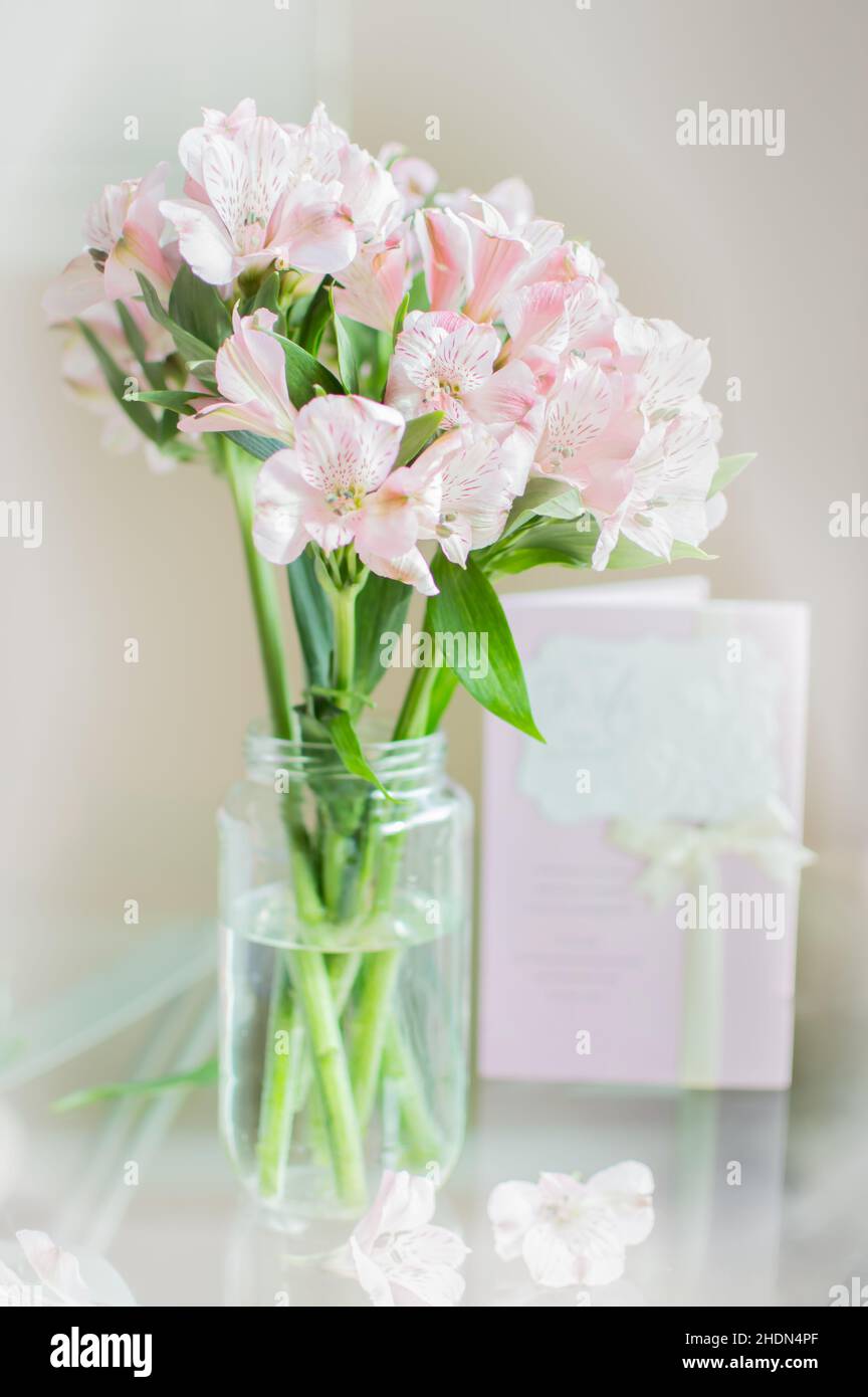 Lily fiori bouquet in un vaso chiaro con una carta sullo sfondo Foto Stock