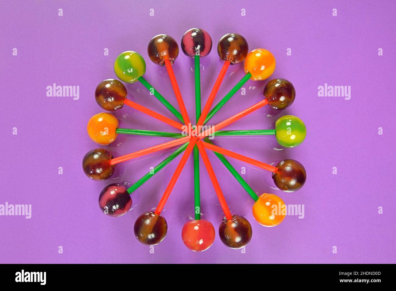 Vari lollipop colorati su sfondo pastello. Lollipop dai colori vivaci e succosi su sfondo lilla. Lollipops sotto forma di un fiore. Caramelle alla frutta Foto Stock