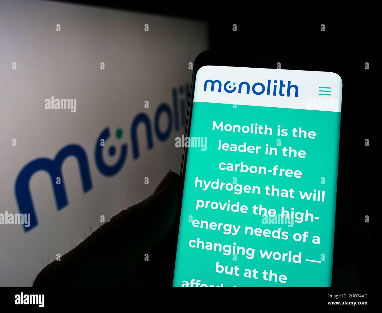 Persona che tiene il cellulare con il sito web della società americana di idrogeno Monolith Inc. Sullo schermo di fronte al logo. Concentrarsi sul centro del display del telefono. Foto Stock