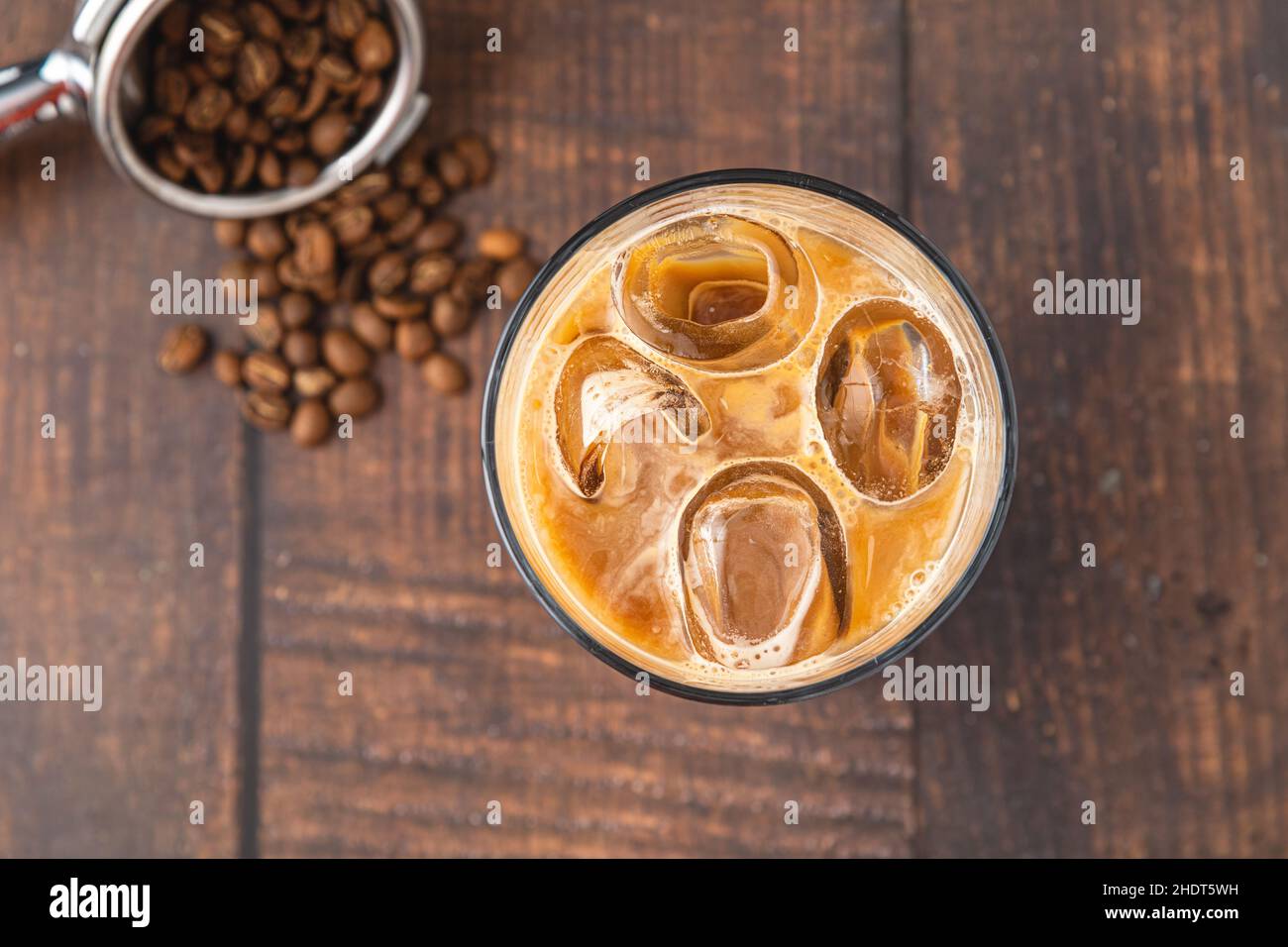 Una tazza di caffè Iced latte con cubetti di ghiaccio posti su un tavolo di legno in una caffetteria Foto Stock