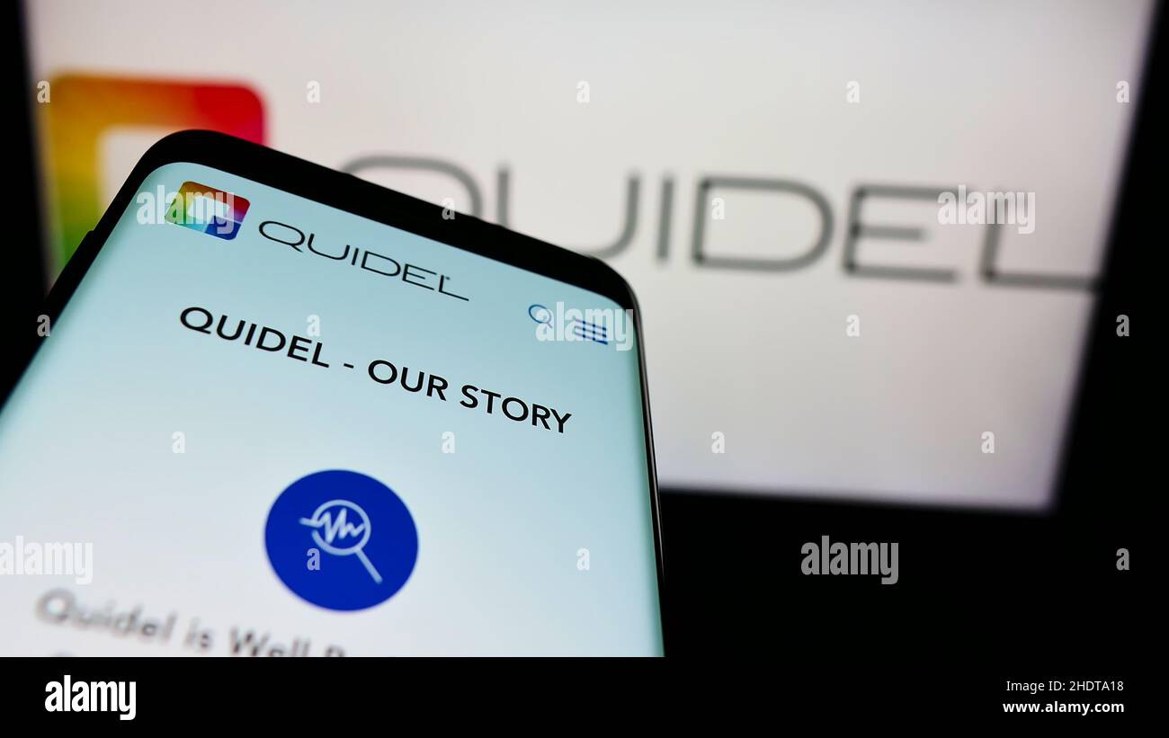 Telefono cellulare con sito web della società americana di diagnostica Quidel Corporation sullo schermo di fronte al logo. Mettere a fuoco sulla parte superiore sinistra del display del telefono. Foto Stock