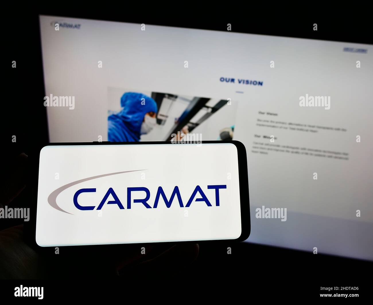 Persona che tiene il cellulare con il logo della società francese di tecnologia medica Carmat SA sullo schermo di fronte alla pagina web. Mettere a fuoco sul display del telefono. Foto Stock