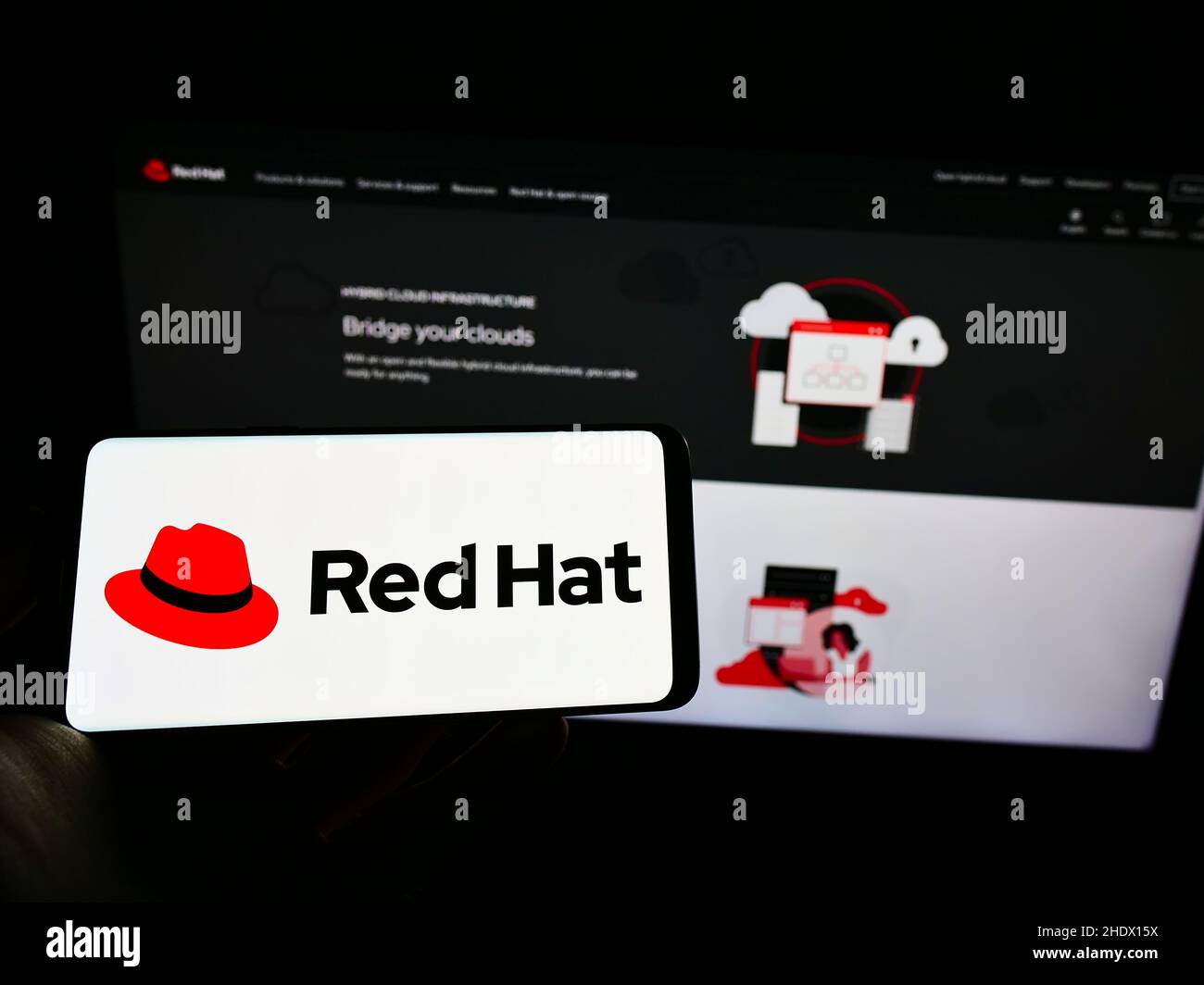 Persona che tiene il telefono cellulare con il logo della società americana di software Red Hat Inc. Sullo schermo di fronte alla pagina web aziendale. Mettere a fuoco sul display del telefono. Foto Stock