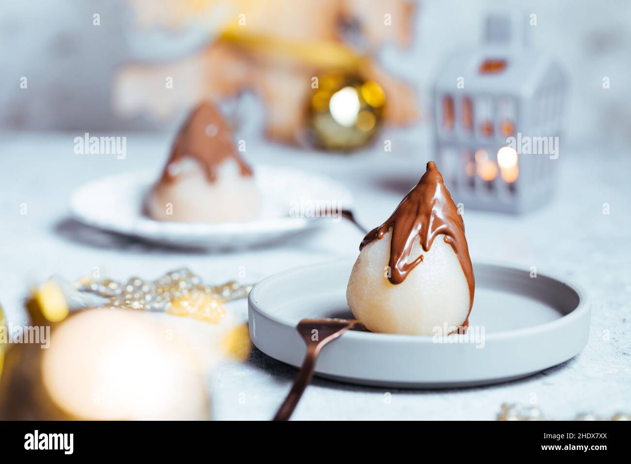 Pera cotta in camicia con cioccolato fondente servito come dessert per celebrare Natale o Capodanno. Decorate in spirito e atmosfera di vacanza con molto deco Foto Stock