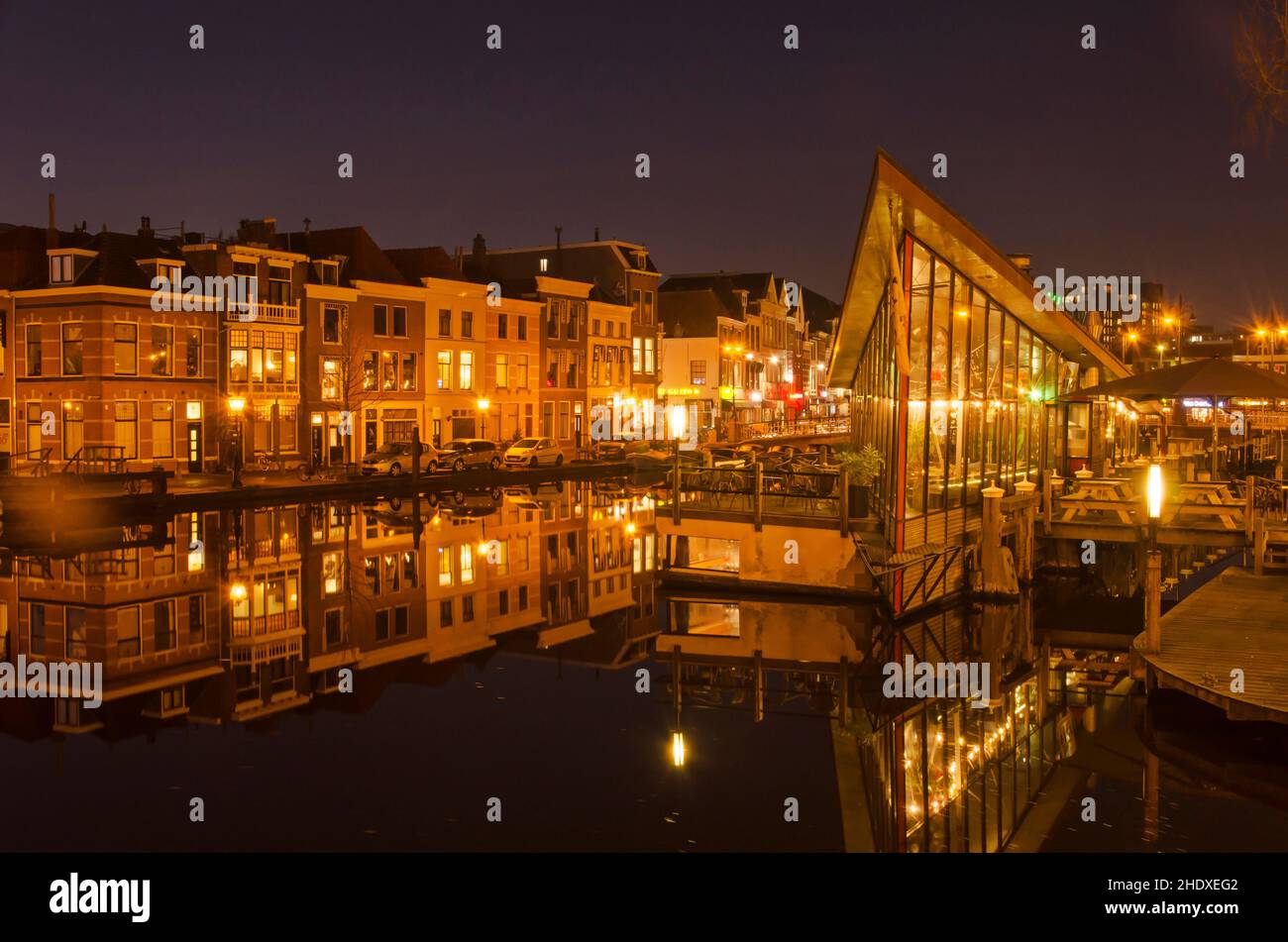 Leiden, Paesi Bassi, 16 dicembre 2021: Case e caffetterie che si riflettono nelle acque fluide del canale Oude Vest in una notte invernale senza vento Foto Stock