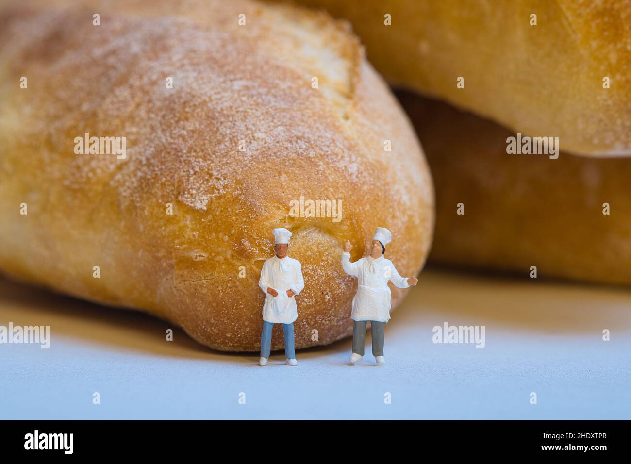 Gli chef in miniatura si trovano di fronte al pane fresco e croccante. Foto Stock