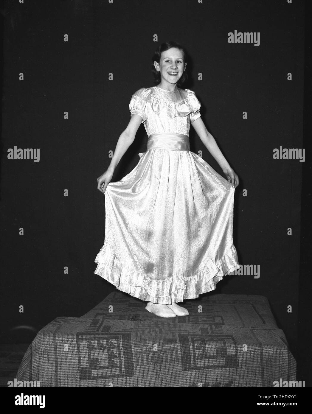 1956, storica, una ragazza in costume per il Carnevale del giorno di maggio, in piedi su una scatola coperta del tappeto per la sua foto, Leeds, Inghilterra, Regno Unito. Foto Stock