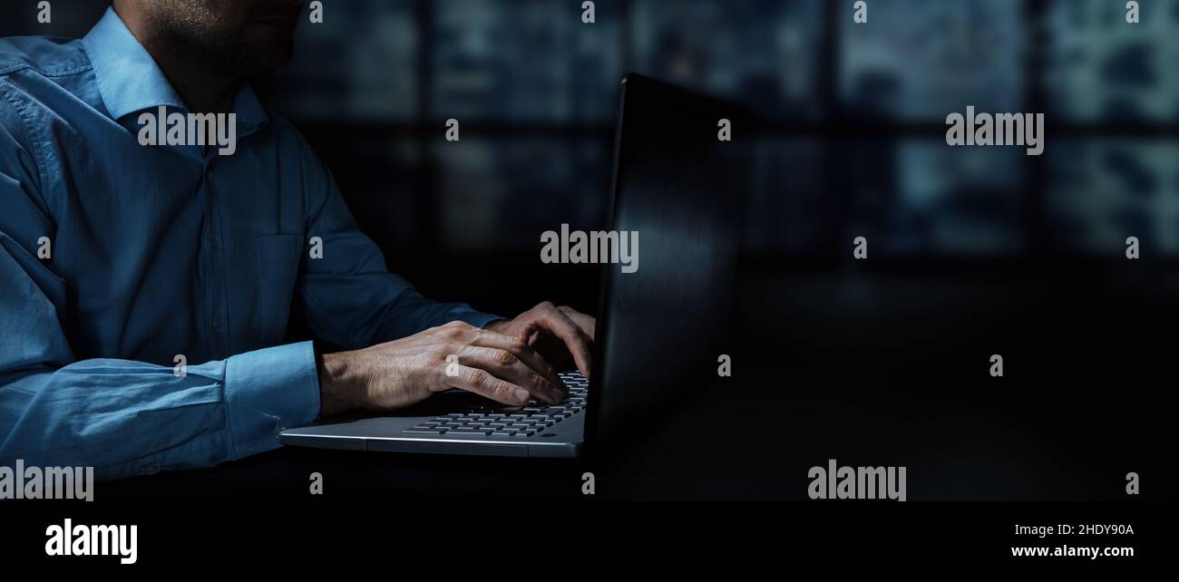 uomo d'affari che lavora su un laptop in un ufficio buio di notte. spazio per la copia dei banner Foto Stock