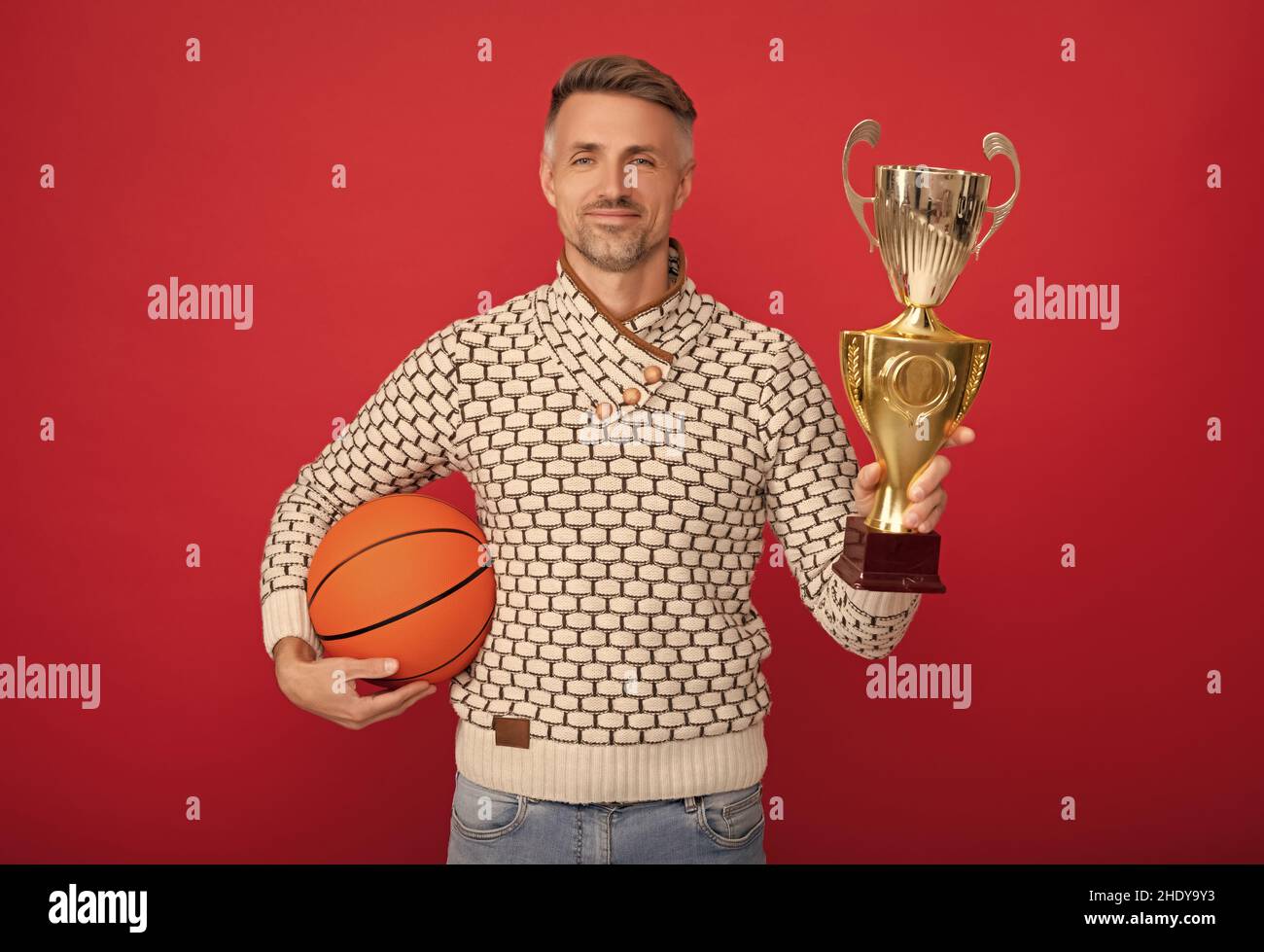 L'uomo felice vince il premio della tazza di basket sfondo rosso, vincitore Foto Stock