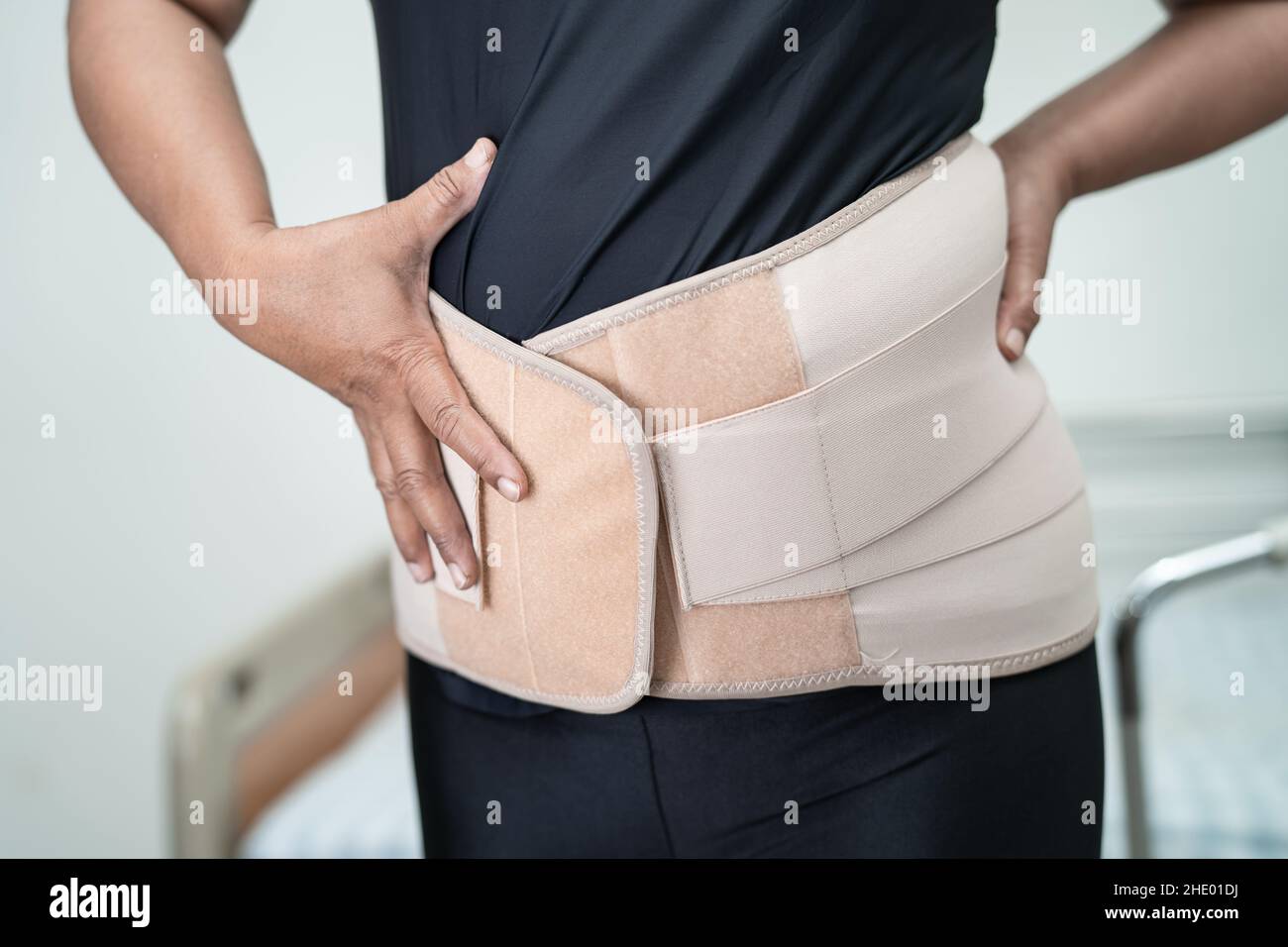 Paziente di signora asiatico che indossa la cintura di sostegno del dolore  alla schiena per lombare ortopedico con scuotipaglia Foto stock - Alamy