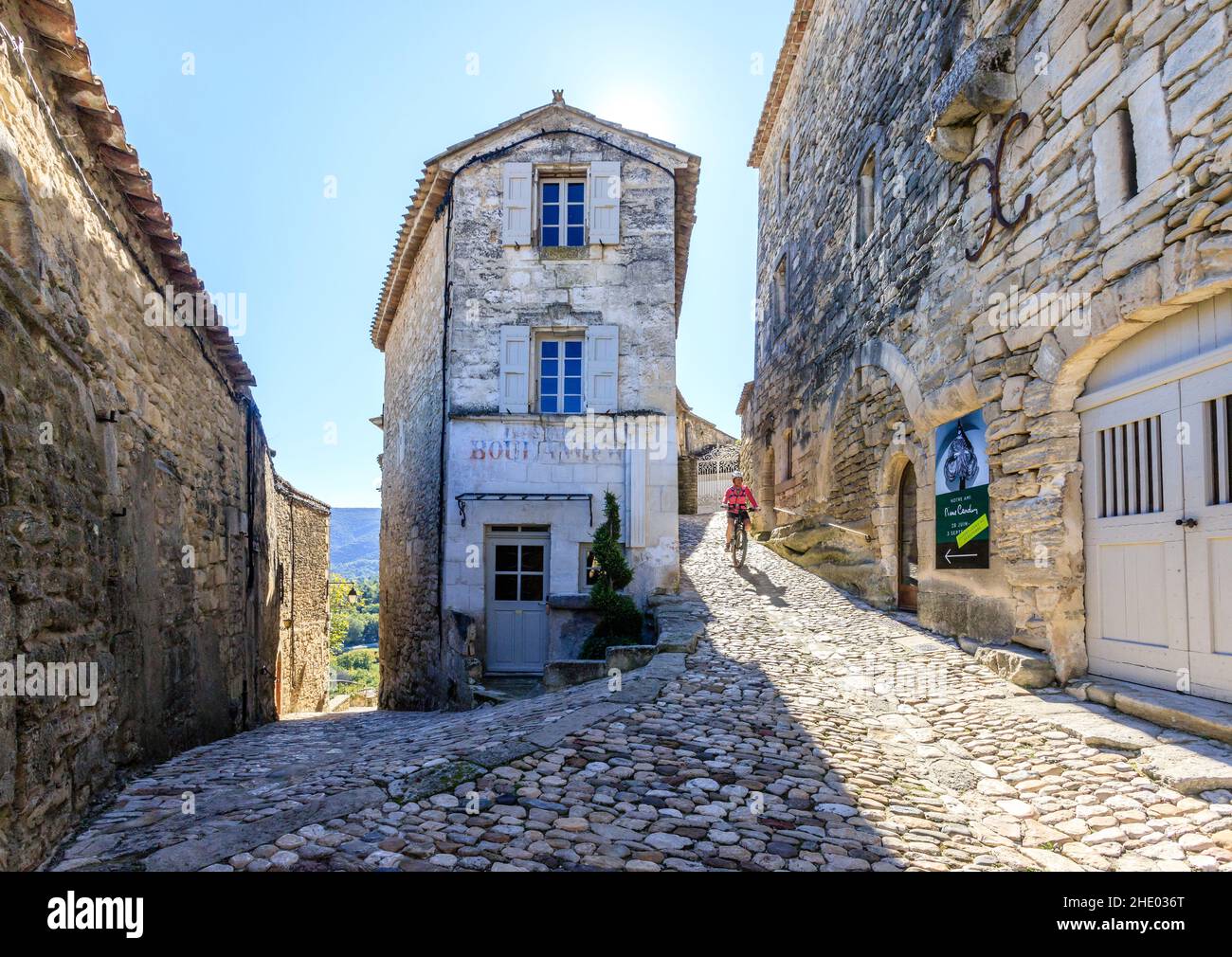 Francia, Vaucluse, Parc Naturel Regional du Luberon (Parco Naturale Regionale del Luberon), Lacoste, vicolo lastricato nel villaggio con un ciclista // Francia, va Foto Stock
